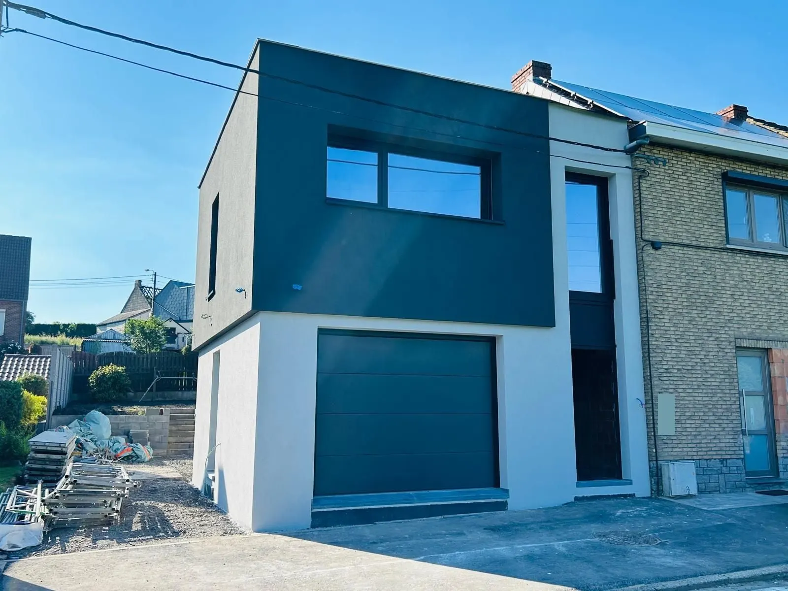 La maison terminée, blanche en bas et anthracite en haut, vue de biais, à Charleroi