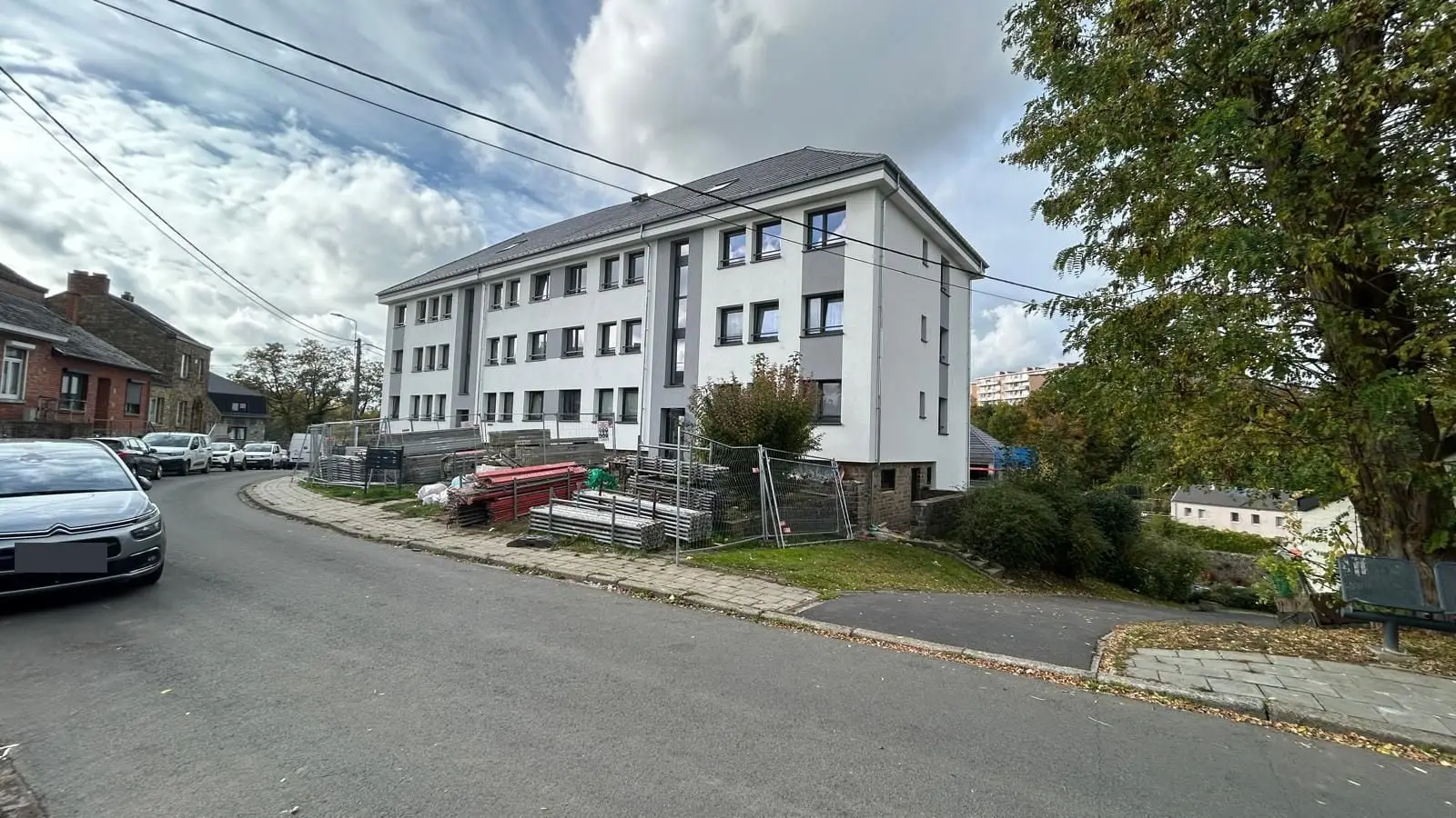 L’immeuble de trois étages terminé, façade blanche et grise, vu de la rue, à Namur