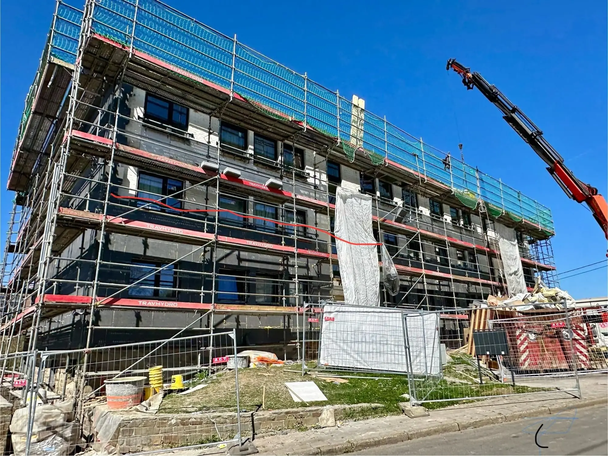 L’immeuble à balcons sous échafaudage, une grue à droite, à Namur
